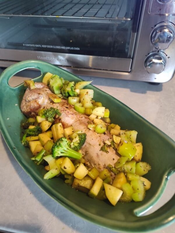 Place the vegetables around the pork tenderloin in a ceramic cooking dish and then place in the oven